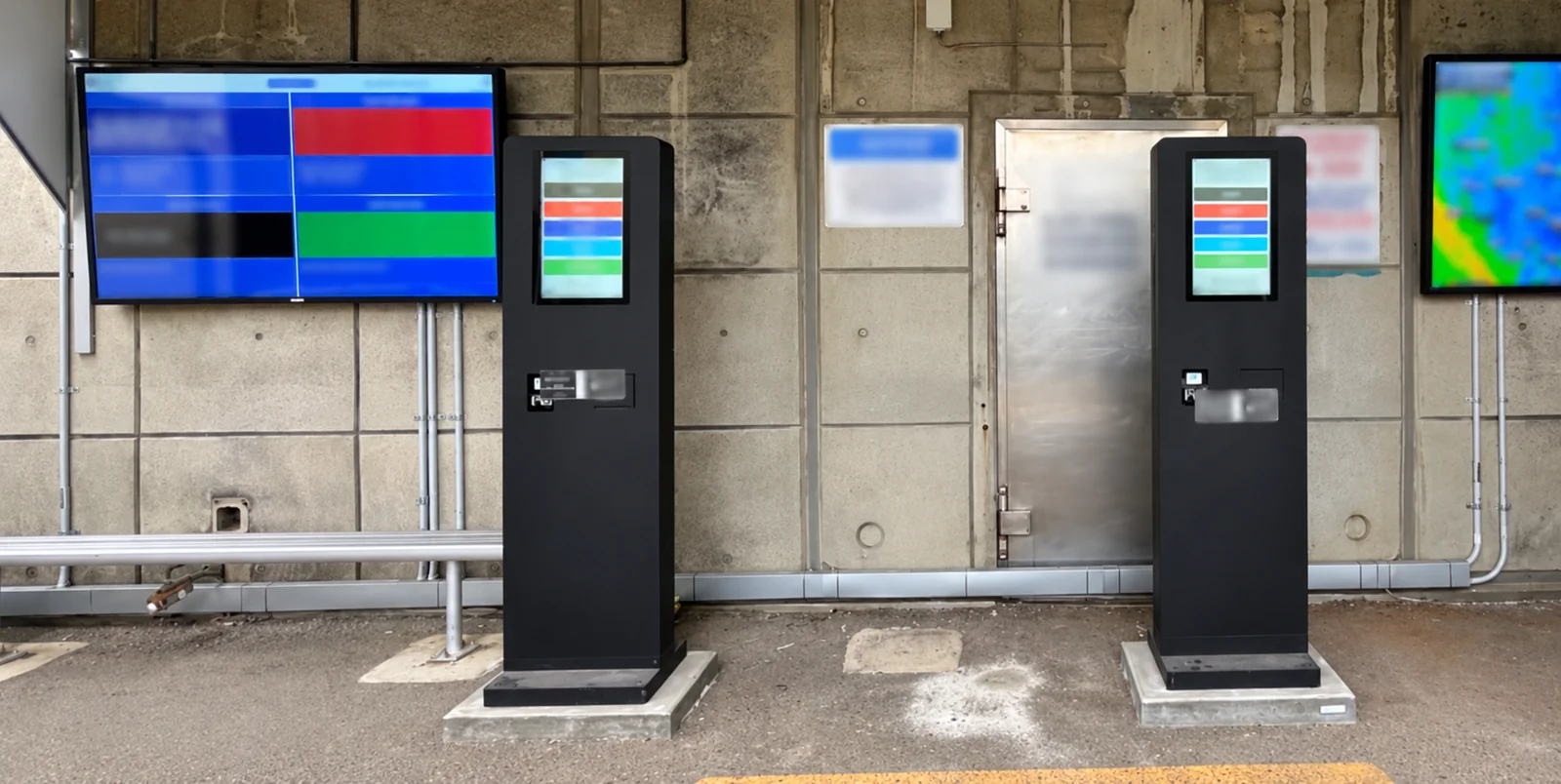 Edited Ampol installation image showing self-service kiosks and wall-mounted displays, with site and screen details obscured